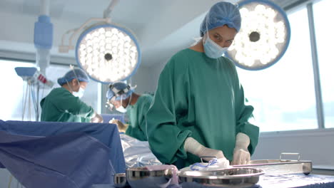 Portrait-of-biracial-female-surgeon-sorting-surgical-tools-in-theatre,-copy-space,-slow-motion