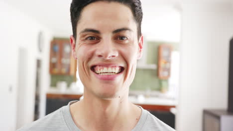 Portrait-of-happy-biracial-man-smiling-in-living-room-at-home,-slow-motion