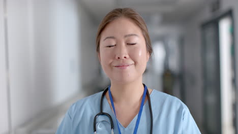 Una-Joven-Enfermera-Asiática-Se-Encuentra-Con-Confianza-En-El-Pasillo-De-Un-Hospital.