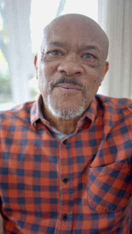 Vertical-video-of-portrait-of-happy-senior-biracial-man-having-video-call-at-home,-slow-motion