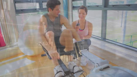Animation-of-financial-data-processing-over-caucasian-man-exercising-with-female-trainer-on-gym