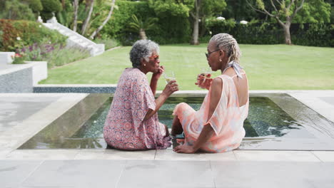Glückliche-ältere-Afroamerikanische-Freundinnen-Mit-Getränken,-Die-Am-Pool-Reden,-Platz-Zum-Kopieren,-Zeitlupe