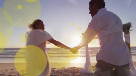 Animation-of-light-spots-over-african-american-couple-getting-married-on-beach