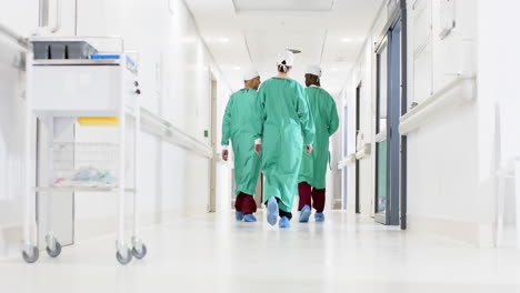 Diverse-male-and-female-surgeons-wearing-surgical-gowns-walking-in-corridor-at-hospital,-slow-motion