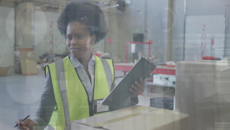 Animation-of-financial-data-processing-over-african-american-woman-working-in-warehouse