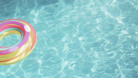 Colourful-inflatable-ring-floating-in-sunny-swimming-pool,-copy-space,-slow-motion