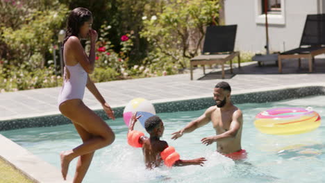 African-american-daughter-jumping-into-swimming-pool-with-happy-family,-slow-motion
