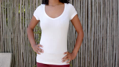 Midsection-of-biracial-woman-in-white-t-shirt-with-hands-on-hips-outdoors,-copy-space,-slow-motion