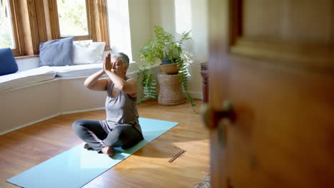 Fokussierte-ältere-Frau-Mit-Gemischter-Abstammung-Meditiert-Zu-Hause-Auf-Yogamatte