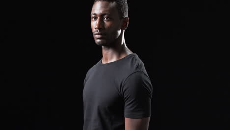 Der-Afroamerikanische-Sportler-Posiert-Selbstbewusst-Vor-Einem-Dunklen-Hintergrund-Auf-Schwarzem-Hintergrund