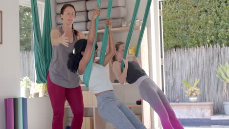 Diverse-Fitness-Teenager-Mädchen-Im-Aerial-Yoga-Kurs-Mit-Weiblicher-Trainerin-In-Einem-Großen-Weißen-Raum,-Zeitlupe