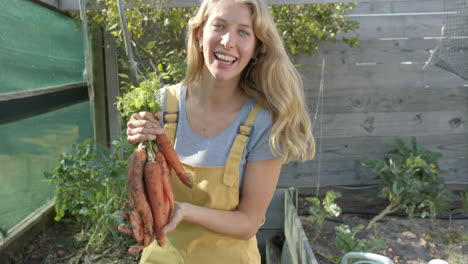 Portrait-of-happy-caucasian-woman-working-in-garden-and-picking-carrots,-slow-motion