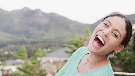 Portrait-of-happy-biracial-woman-laughing-standing-on-balcony-at-home,-slow-motion