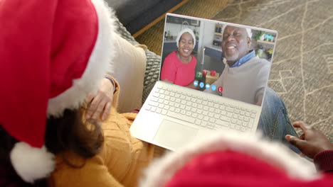 Happy-diverse-couple-and-senior-parents-having-christmas-laptop-video-call,-slow-motion