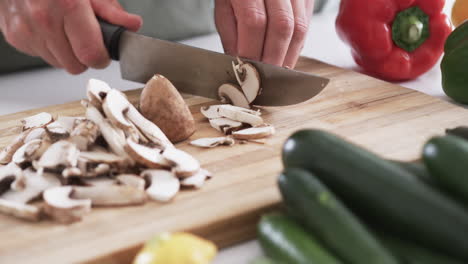 Close-up-of-hands-chopping-mushrooms-on-a-cutting-board-in-a-home-kitchen