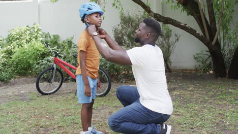 African-American-father-helps-a-son-with-his-helmet-outdoors