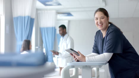 Portrait-of-caucasian-female-doctor-using-tablet-and-smiling-in-ward,-copy-space,-slow-motion