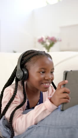 Vertical-video-of-happy-african-american-girl-using-tablet-at-home,-slow-motion