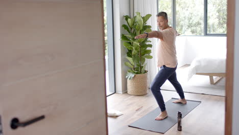 Senior-biracial-man-exercising,-practicing-yoga-at-home