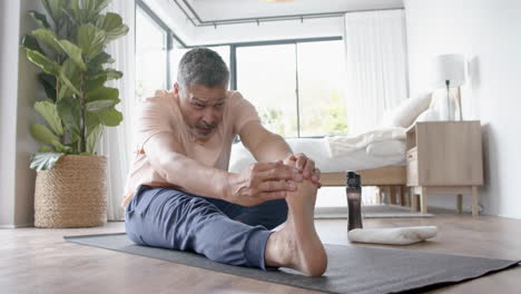 Fokussierter-älterer-Mann-Mit-Gemischter-Abstammung,-Der-Zu-Hause-Yoga-Stretching-Praktiziert,-Zeitlupe