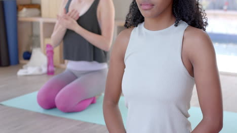Focused-diverse-fitness-women-exercising-and-meditating-on-mat-in-white-room,-slow-motion