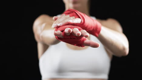 Young-Caucasian-woman-boxer-in-a-fighter's-stance-on-a-black-background