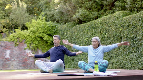 Focused-diverse-senior-couple-practicing-yoga-meditation-in-garden