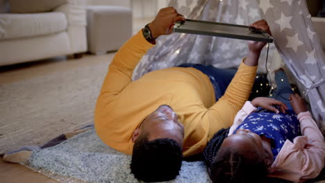Happy-african-american-father-with-daughter-using-tablet-at-teepee,-slow-motion