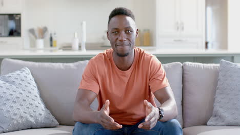 Glücklicher-Afroamerikanischer-Mann-Mit-Videoanruf-Im-Sonnigen-Wohnzimmer,-Zeitlupe