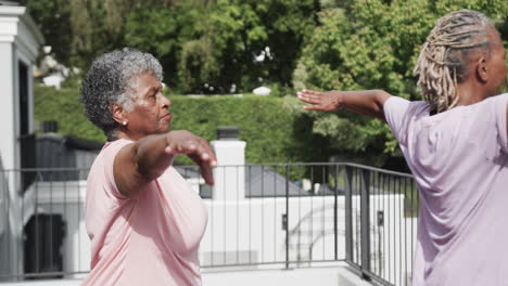 Fokussierte-ältere-Afroamerikanische-Freundinnen,-Die-Yoga-Praktizieren-Und-Auf-Dem-Balkon-Stehen,-Zeitlupe