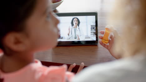 Biracial-female-doctor-having-tablet-video-call-with-mother-and-sick-daughter-at-home,-slow-motion