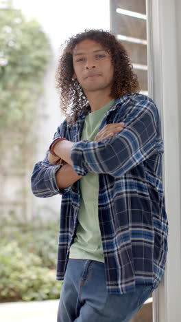 Vertical-video-of-portrait-of-biracial-man-with-long-curly-hair-at-home,-slow-motion