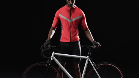 African-American-cyclist-stands-with-his-road-bike-on-a-black-background