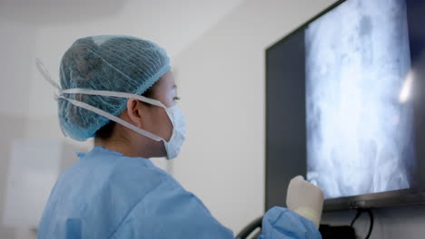 Asian-female-surgeon-looking-at-x-ray-scans-in-operating-theatre,-slow-motion