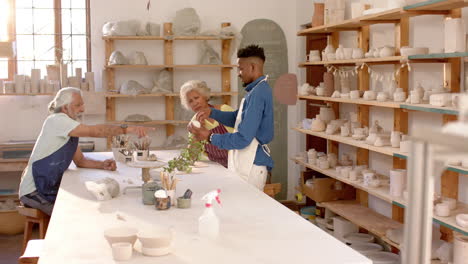 Happy-diverse-group-of-potters-discussing-about-work-in-pottery-studio