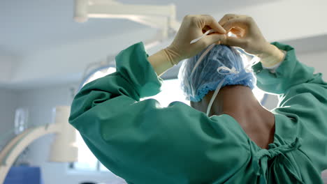 Afroamerikanischer-Chirurg-Bindet-Gesichtsmaske-Im-Operationssaal,-Zeitlupe