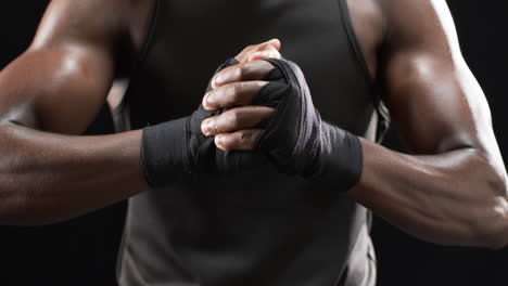 Afroamerikanischer-Boxer-Umschließt-Seine-Hände-Zum-Boxen-Auf-Schwarzem-Hintergrund