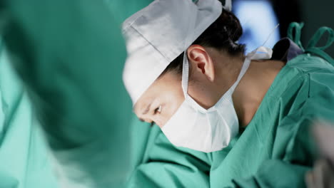 Asian-female-surgeon-operating-on-patient-in-operating-theatre-at-hospital,-slow-motion