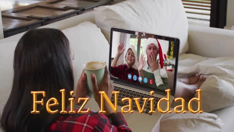 Animation-of-feliz-navidad-text-over-diverse-couple-on-laptop-screen-at-christmas