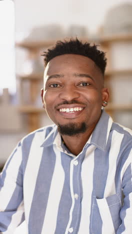 Glücklicher-Afroamerikanischer-Mann-Mit-Bart,-Der-Im-Töpferstudio-Sitzt-Und-Lächelt,-Zeitlupe