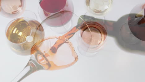 Composite-of-rose-wine-being-poured-into-glass-over-wine-glasses-on-white-background