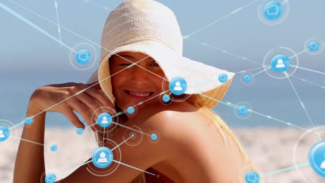 Animation-of-connected-profile-icons-over-smiling-caucasian-woman-wearing-hat-and-sitting-on-beach
