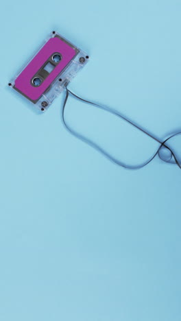 Vertical-video-of-retro-tape-with-pink-label-and-copy-space-on-blue-background