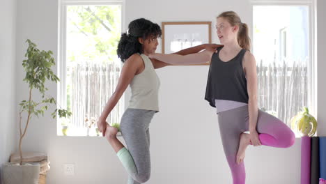 Happy-diverse-fitness-teenage-girls-exercising-and-stretching-in-white-room,-slow-motion