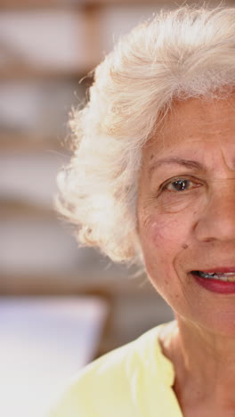 Half-face-of-appy-biracial-female-potter-with-gray-hair-smiling-in-pottery-studio,-slow-motion