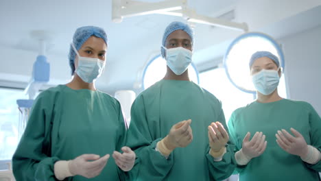 Portrait-of-three-diverse-male-and-female-surgeons-in-operating-theatre,-slow-motion