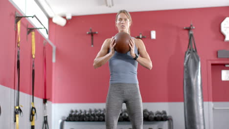 Fit-young-Caucasian-woman-squatting-with-a-medicine-ball-at-the-gym