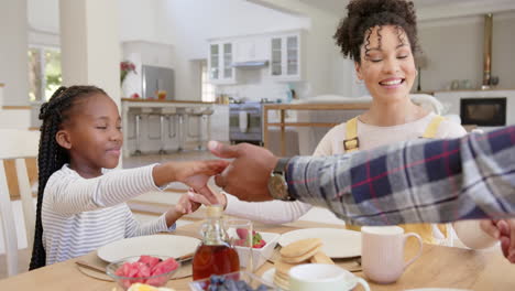 Glückliche-Afroamerikanische-Eltern-Und-Tochter-Beten-Vor-Dem-Frühstück-Zu-Hause,-Zeitlupe