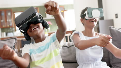 Happy-african-american-brother-and-sister-using-vr-headsets-on-sofa,-slow-motion
