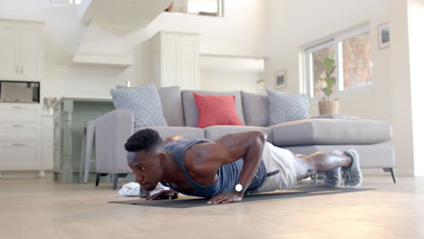 Focused-african-american-man-doing-push-ups-in-sunny-living-room,-slow-motion